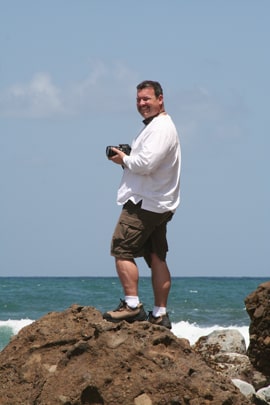 Dan Refner with Camera on ocean rocks