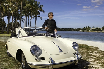 Surfers carrying boards by the shoreline on a sunny Florida morning.
