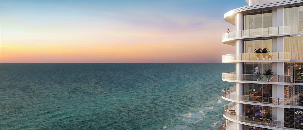 Luxury high-rise condominium with curved balconies overlooking the ocean at sunset.