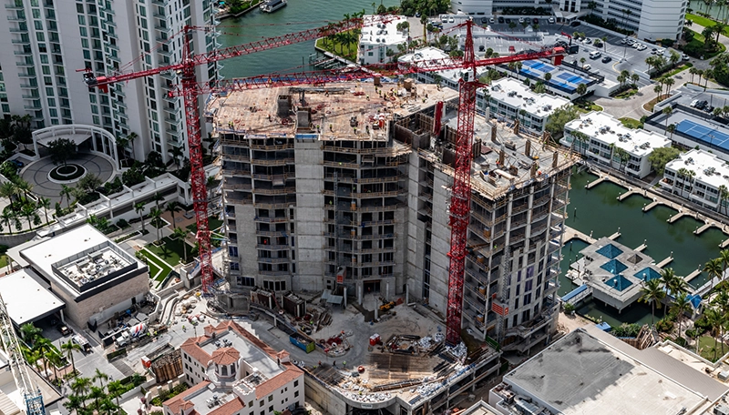 High-rise condominium under construction with cranes in an urban waterfront setting