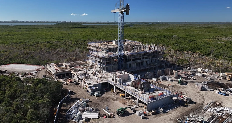 Aerial view of a high-rise condominium under construction with cranes and concrete structure.