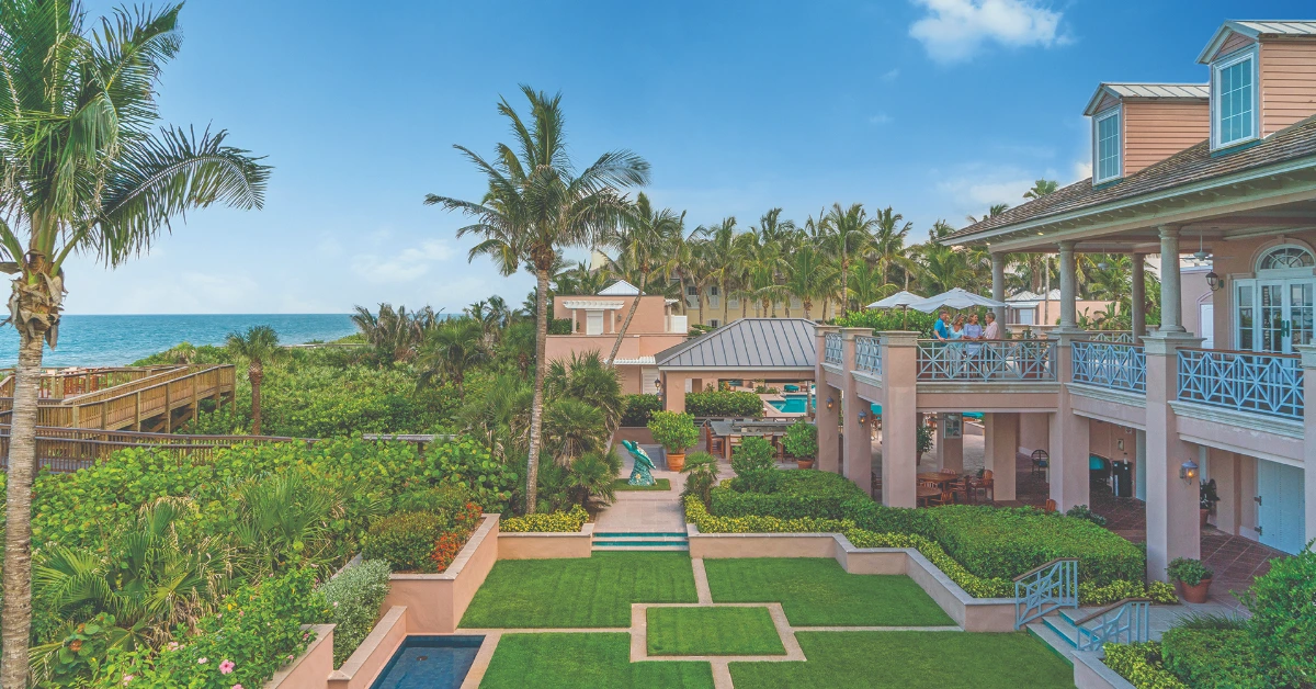 Oceanfront private club with palm trees, landscaped gardens, and terrace overlooking the sea