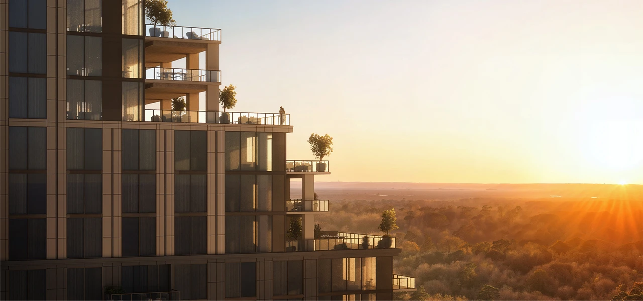 Contemporary condo tower with stacked balconies at sunset overlooking a broad tree lined horizon
