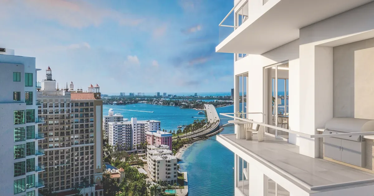 Stunning high rise balcony with built in grill overlooks Biscayne Bay and Miamis waterfront skyline on a clear sun drenched day